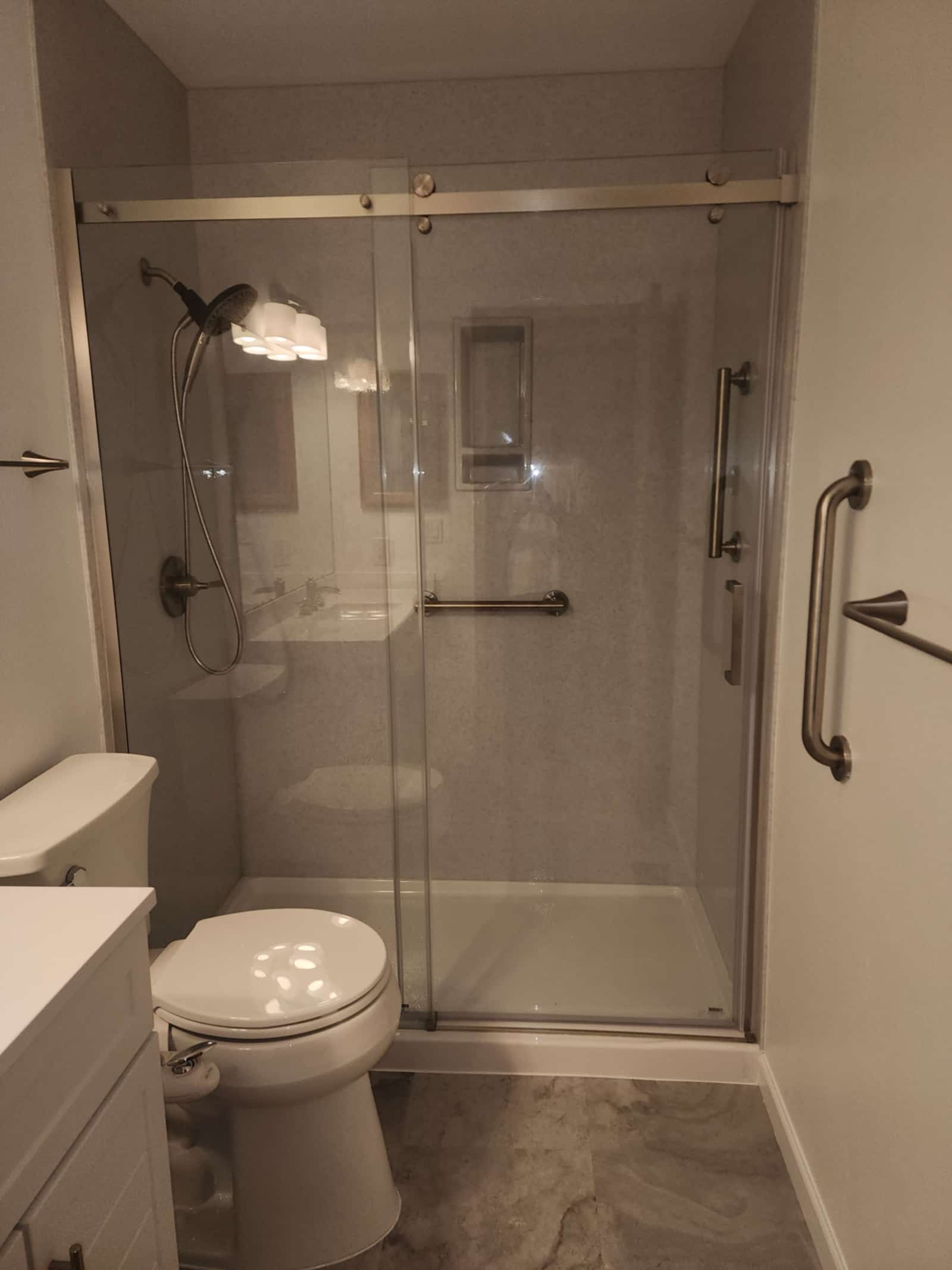 Bathroom with a wide walk-in shower, grab rails and a white vanity with storage
