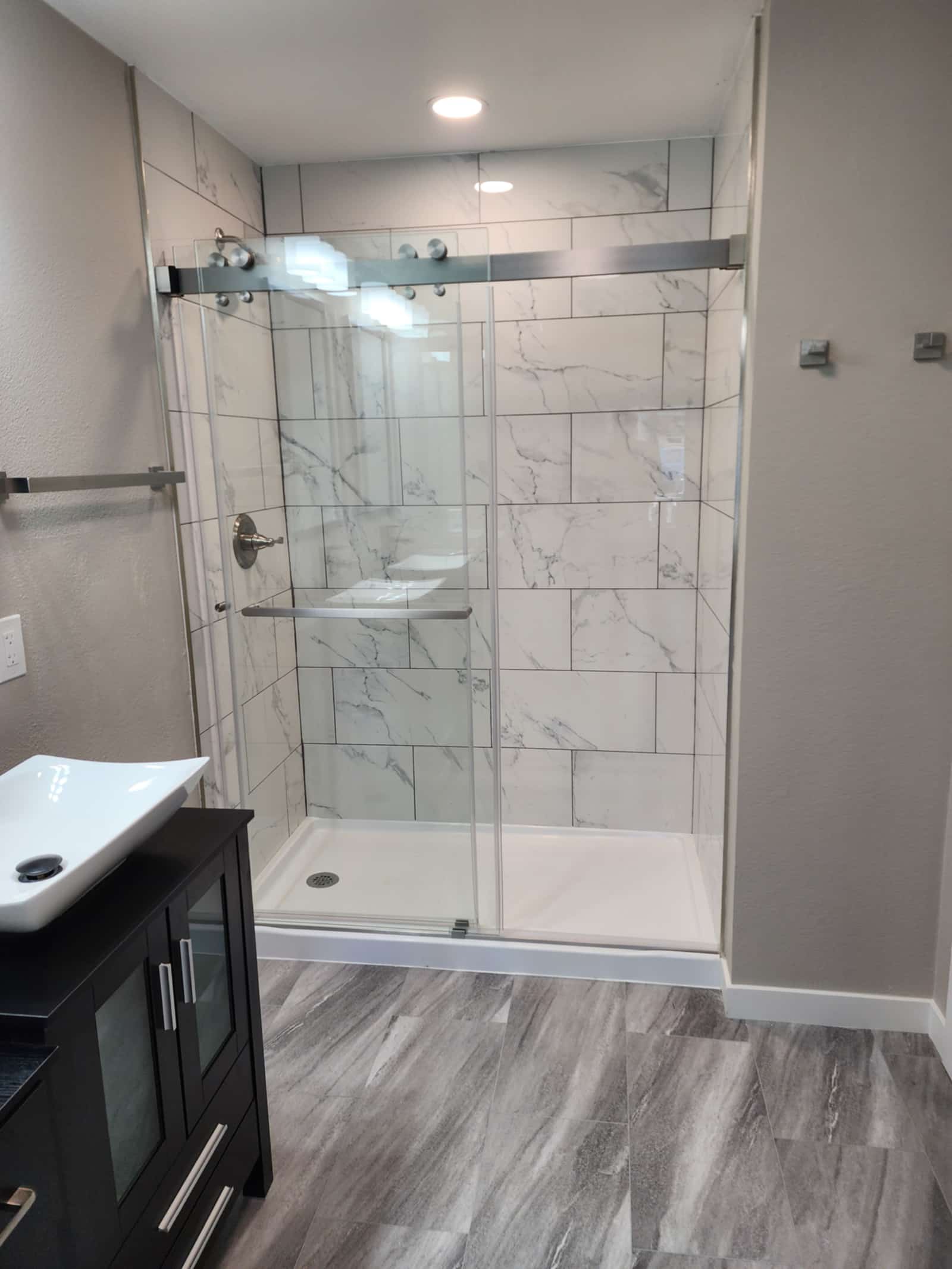 Walk-in shower in marble-look tile with a glass screen and a built-in niche