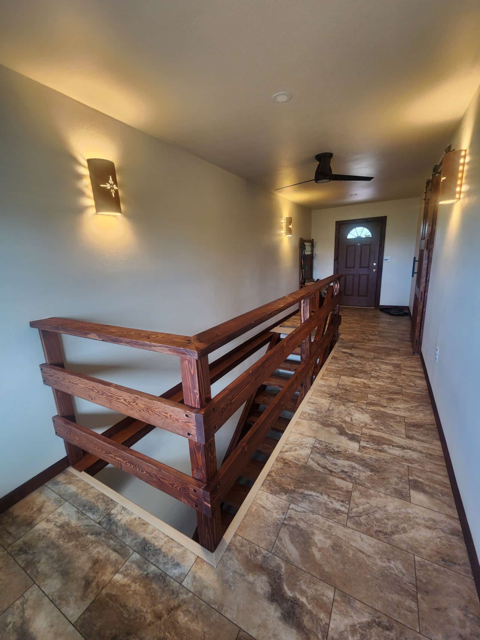 Interior stair with a heavy timber handrail and open treads, looking down a hallway