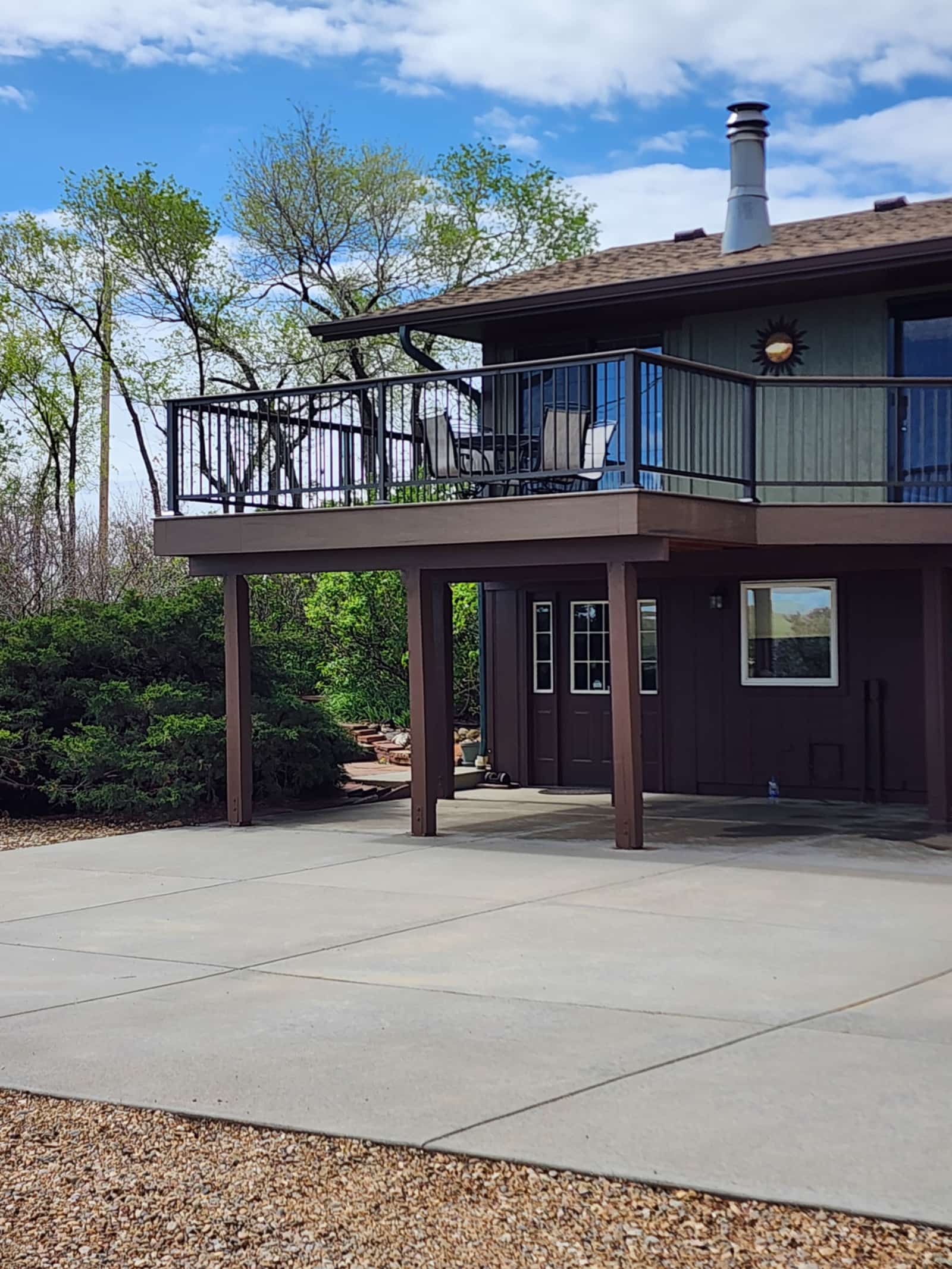 Elevated deck with black railings wrapping the upper floor of a green two-story house