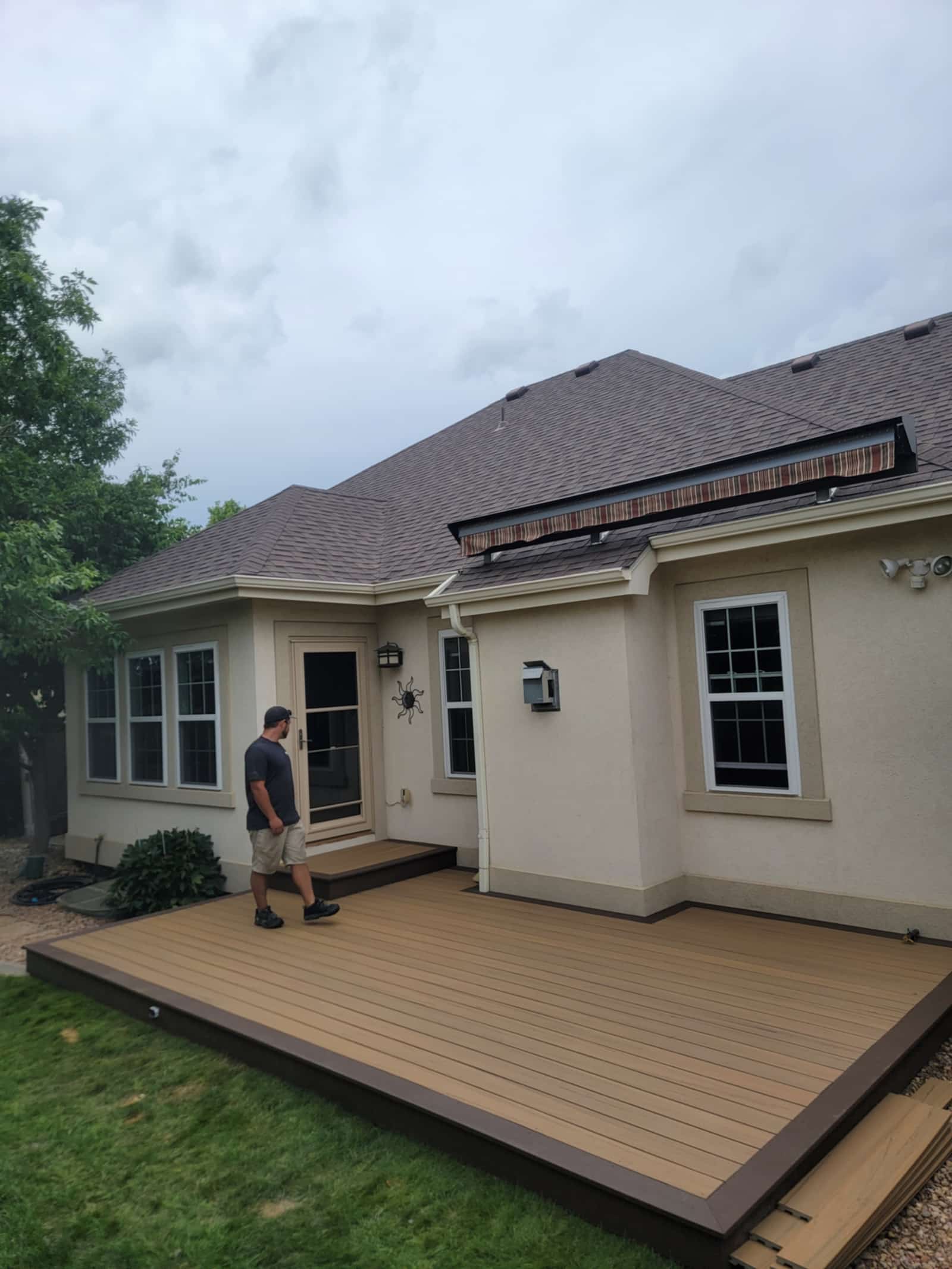 Low-profile tan composite deck wrapping the back of a cream stucco house