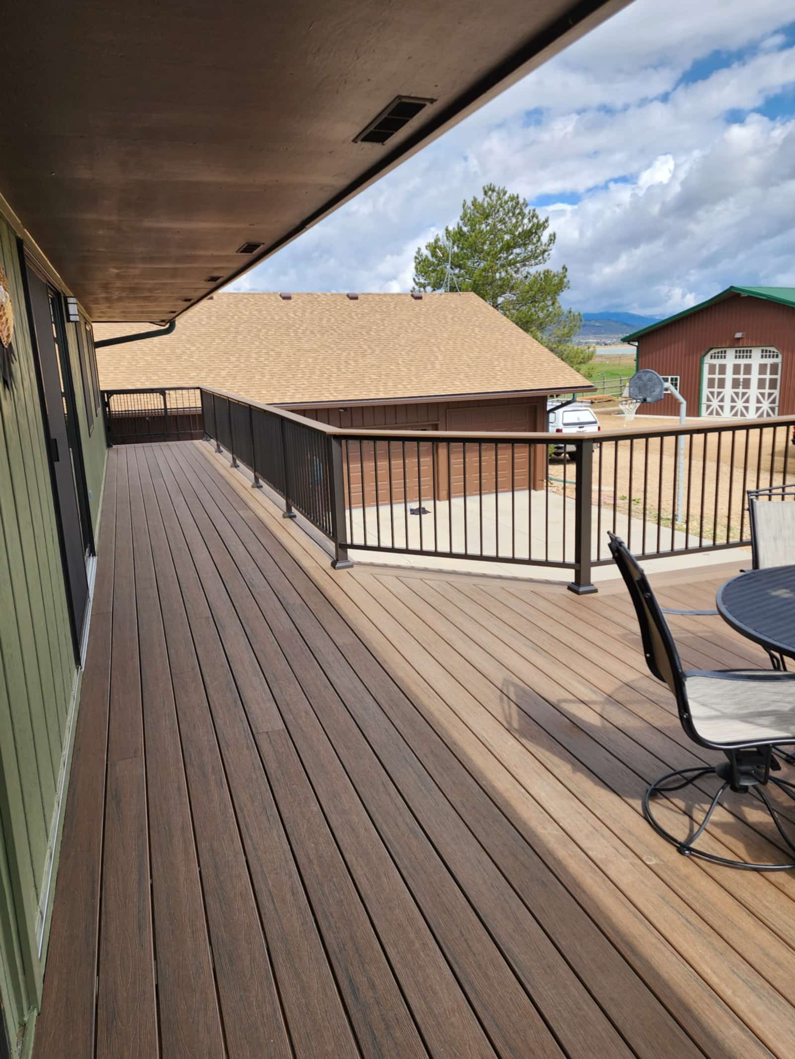 Deck with black railings and a dining table looking out over open countryside