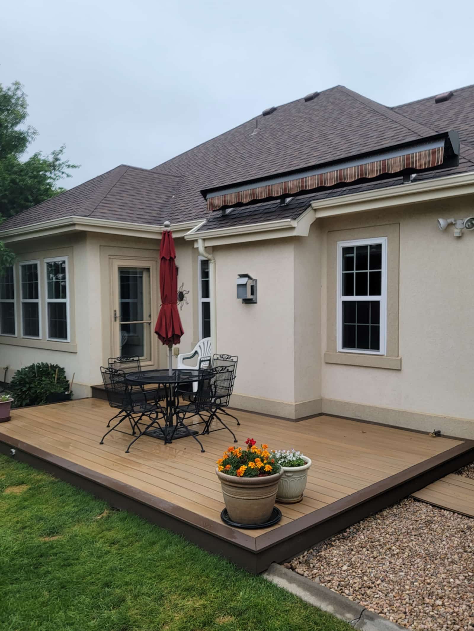Covered patio with a red umbrella and a patio set against a cream stucco house