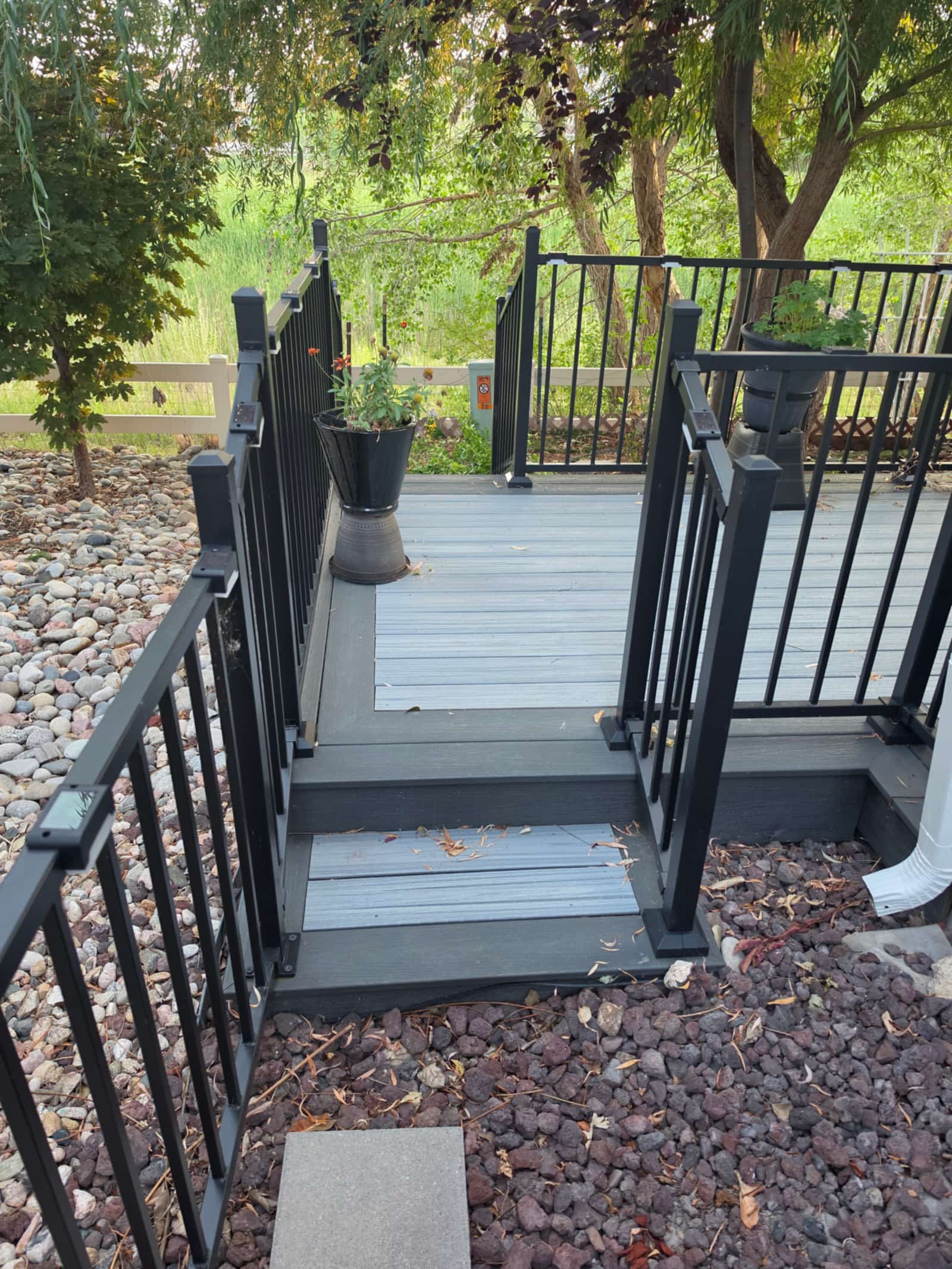 Gray composite deck with a wide staircase and black railings between two levels