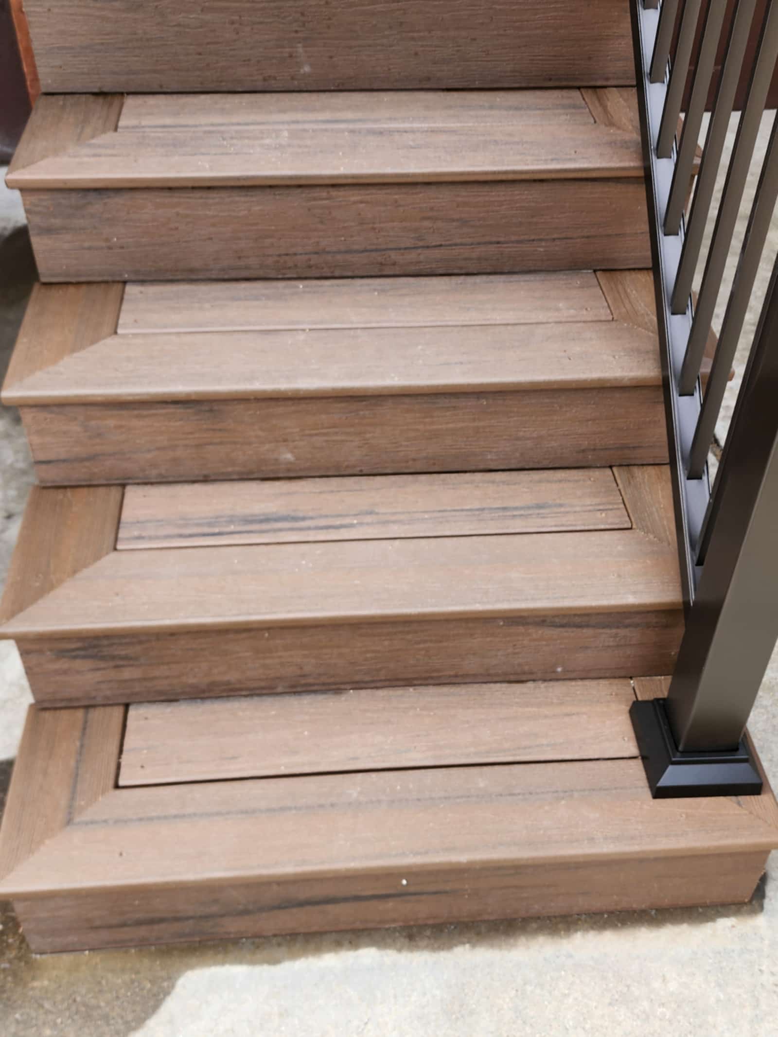 Close view of wide timber deck steps with black railing posts