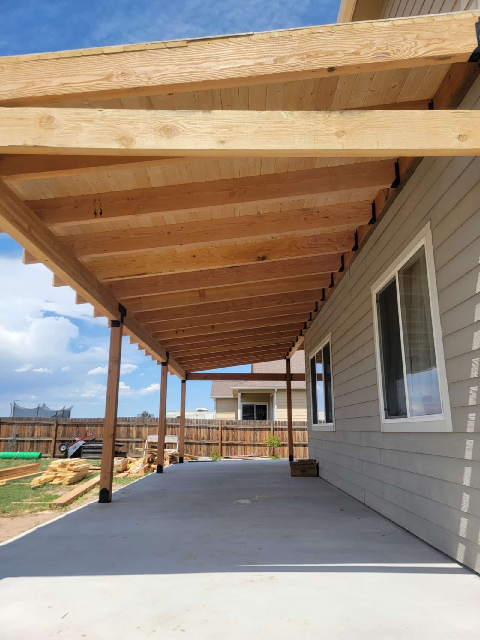 Underside of a covered patio showing the tongue and groove ceiling and supporting posts