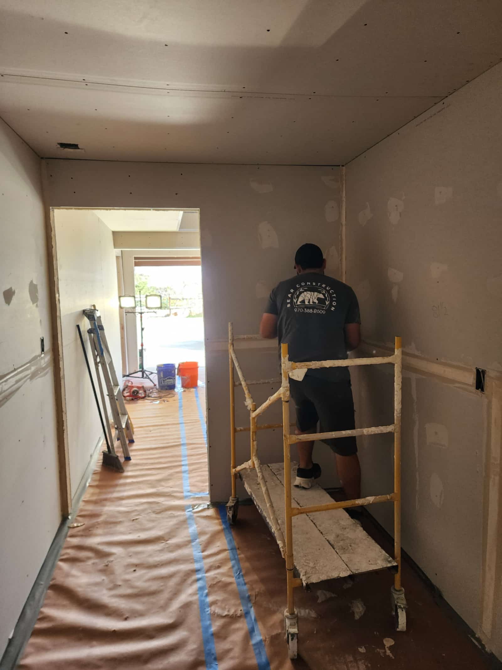 A carpenter working on a taped and prepared interior during a whole-home remodel