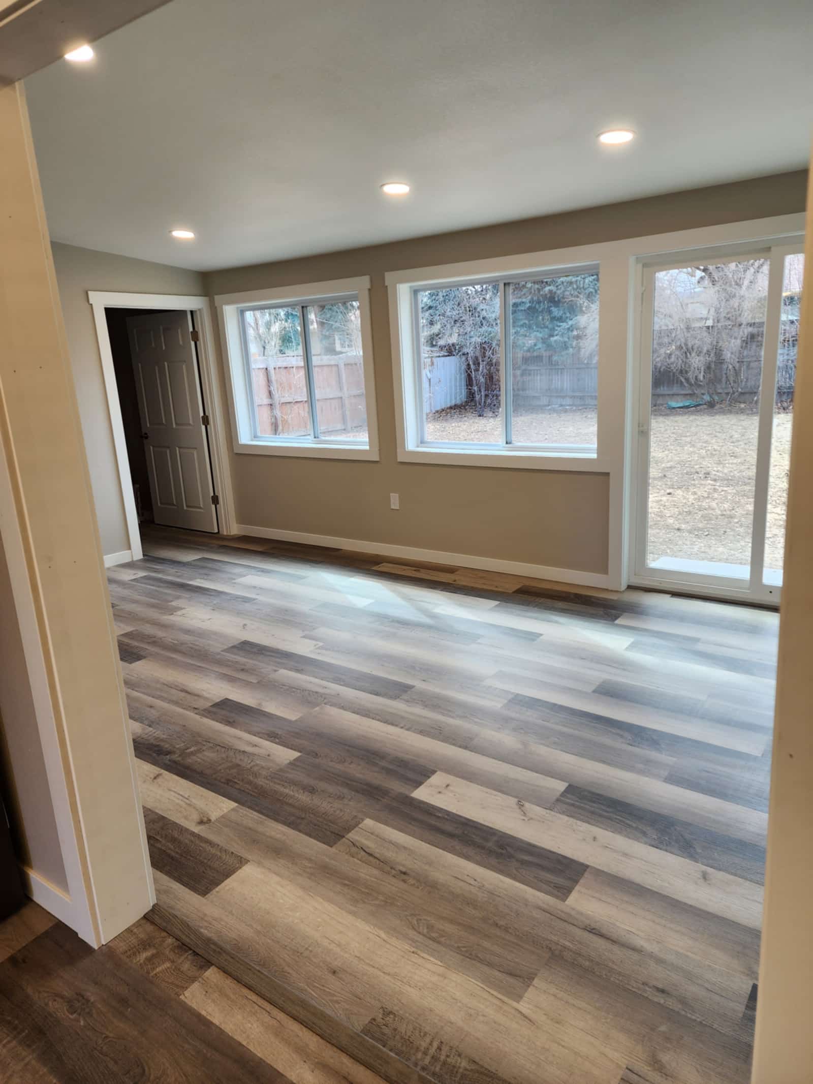 Finished living room with new plank flooring, recessed lighting and a wide slider opening onto the garden